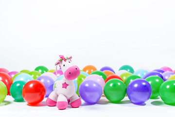 Pink toy horse with multi-colored balloons on a white background