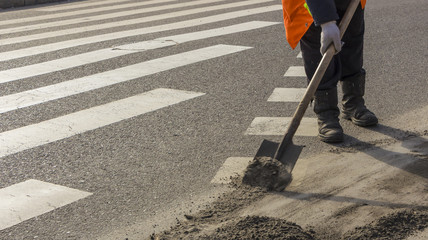 Road worker cleans the road from the sand