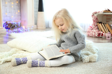 Cute little girl reading book at home