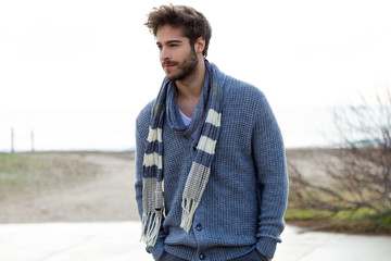 Handsome young man posing in a cold winter on the beach.
