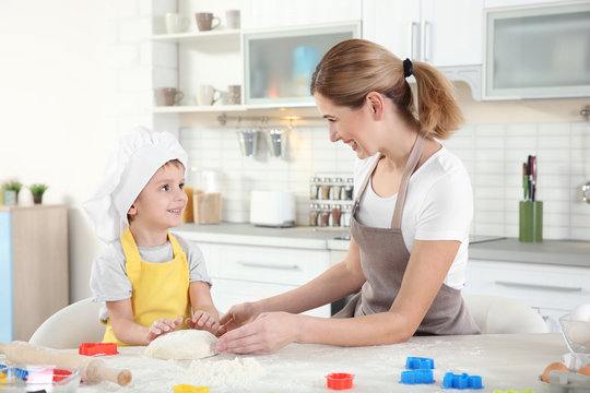 Young mother with son making biscuits on table