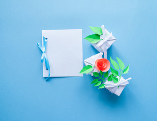 white card with white gift with paper flower on blue background