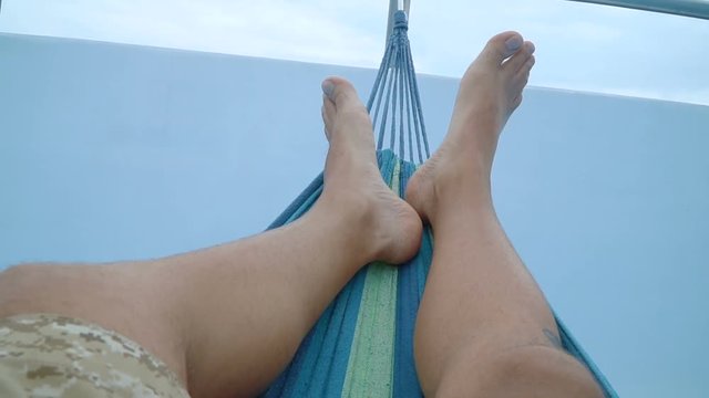 feet of a man lying down and swinging in a hammock. Full HD stock footage.
