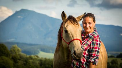 Girl with a blue and red mapped shirt with a horse in Slovakia