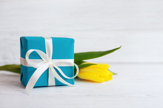 Packaged gift and yellow tulip. Concept of holiday, birthday, Easter, March 8.