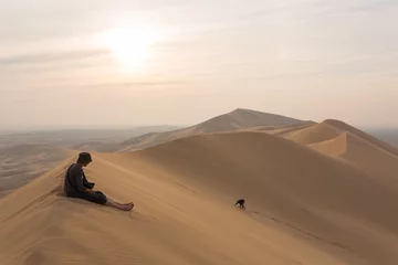  One person sits on top of the dunes of the desert, and the other climbs to the top © vova1675