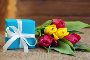 Beautiful tulips and blue gift. Greeting. Concept of holiday, birthday, Easter, March 8.