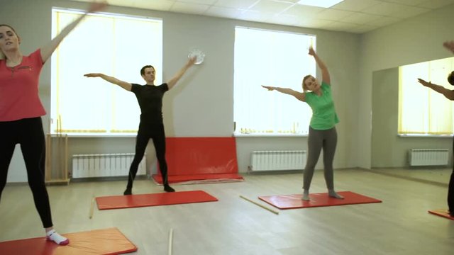 A group of people practicing exercises of gymnastics with trainer in sports hall. HD