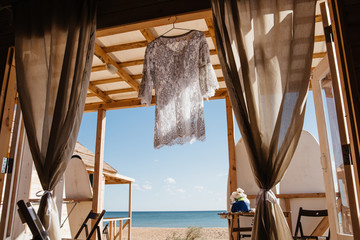 Summer woman beach dress on seaview from wooden hut on beach. Luxury resort summer vacation concept.