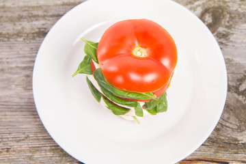 Caprese salad - tomato with mozzarella and basil on a wooden background