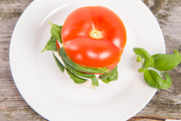 Caprese salad - tomato with mozzarella and basil on a wooden background