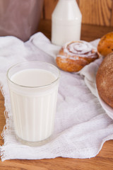 Glass of milk and plate with assortment of various fresh pastries and small bottle of milk on the background. Breakfast concept, selective focus