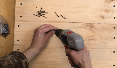 Hands screwdrivers screwed screws in wooden boards