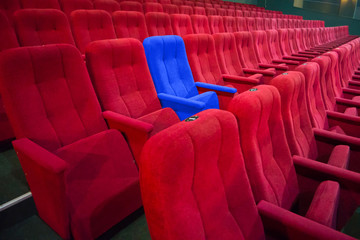 Blue chair between rows of red seats