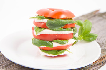 Caprese salad - tomato with mozzarella and basil on a wooden background