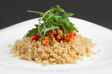 Traditional russian lenten salad with pearl barley, tomato, marrow squash, corn, zucchini and paprika.