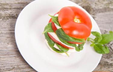 Caprese salad - tomato with mozzarella and basil on a wooden background