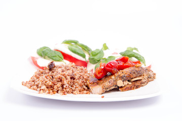 A Meal: Roast pork, kasha, and caprese salad with basil on a white plate