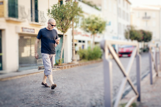 Man Crossing The Street Looking At His Phone