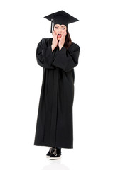 Full length emotional portrait of a young amazed or surprised graduation girl in mantle isolated on white background.