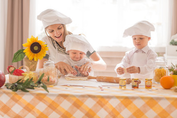 happy mom and her children make cookies in the kitchen