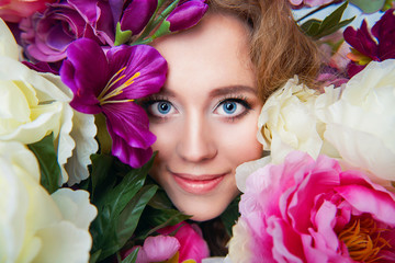 Portrait of smiling beautiful young girl in spring colorful flowers