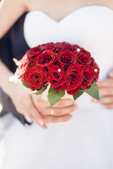 Bride and groom close up with red bouquet
