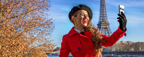 woman on embankment near Eiffel tower in Paris taking selfie