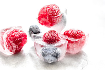 Ice cubes with frozen berries on white background