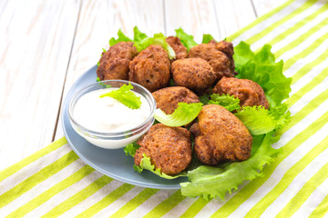 Acaraje or akara snack with green salad and sour cream