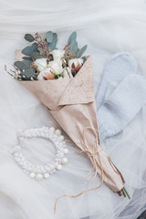 Bouquet with mittens and necklace on white tulle