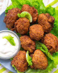 Acaraje or akara snack with green salad and sour cream
