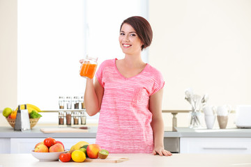 Young beautiful woman with orange juice in the kitchen