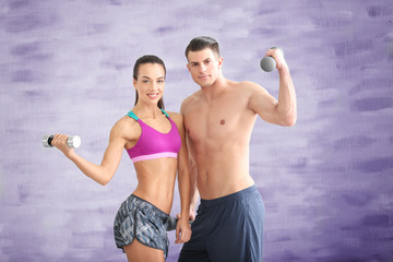 Fototapeta na wymiar Young sporty couple with dumbbells in gym