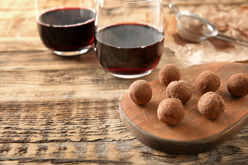 Tasty chocolate truffles and red wine on wooden table