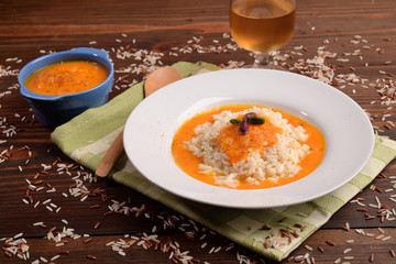 Cream of pumpkin soup with pistachio rice and onion on table