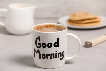Words GOOD MORNING written on cup with breakfast on background