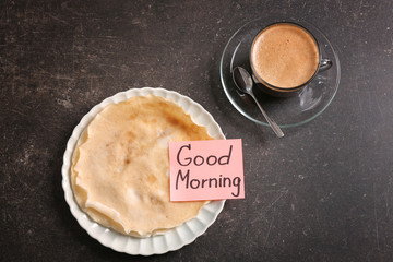 Cup of coffee, pancakes and note GOOD MORNING on kitchen table