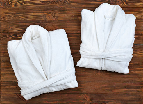 Folded spa bathrobes on wooden background