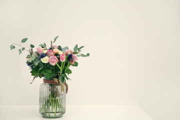 Glass vase with beautiful bouquet on light background