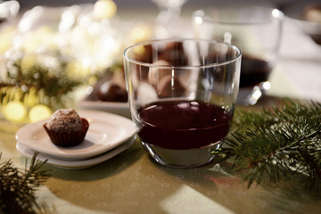 Glass of wine and chocolate candy on decorated table closeup