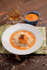 Cream of pumpkin soup with pistachio rice and onion on table