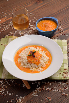 Cream of pumpkin soup with pistachio rice and onion on table