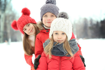 Fototapeta premium Happy children in red warm clothing having fun outdoors in winter