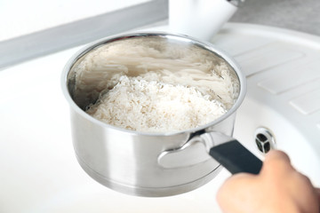 Woman rinsing rice in saucepan
