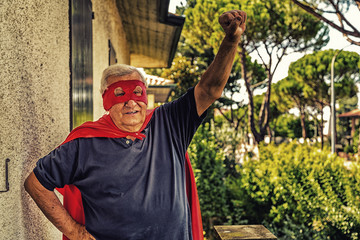 senior posing as superhero with red cloak and mask