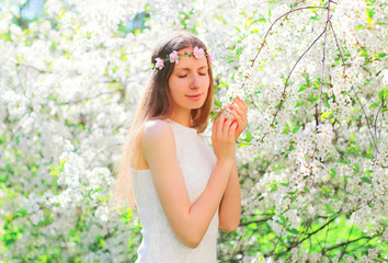 Beautiful young woman with floral headband over flowering garden background