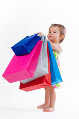 Little girl standing with colorful paper bags isolated on white background.