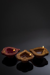 Hindu religion and Indian celebration of Diwali festival concept with group of burning clay diyas, festive oil lamps with illumination and reflection against a black background with copy space