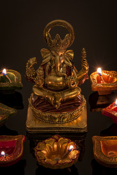 Hindu religion and Indian celebration of Diwali festival concept with diya lamps and candles around the Lord Ganesh. Ganesha is the patron of arts and sciences and the deva of intellect and wisdom